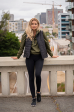 Load image into Gallery viewer, Woman standing against a bridge railing wearing our Womens Lightweight Black Puffer Vest
